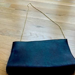 Oversized black clutch with gold chain and tassels
